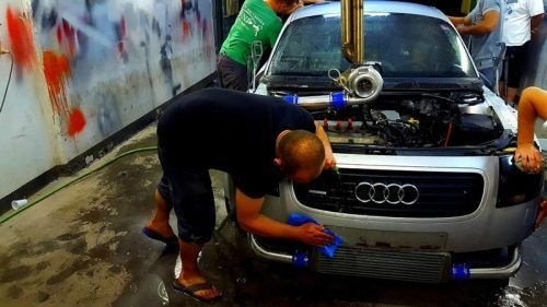 Мужчина моет свою машину после ремонта